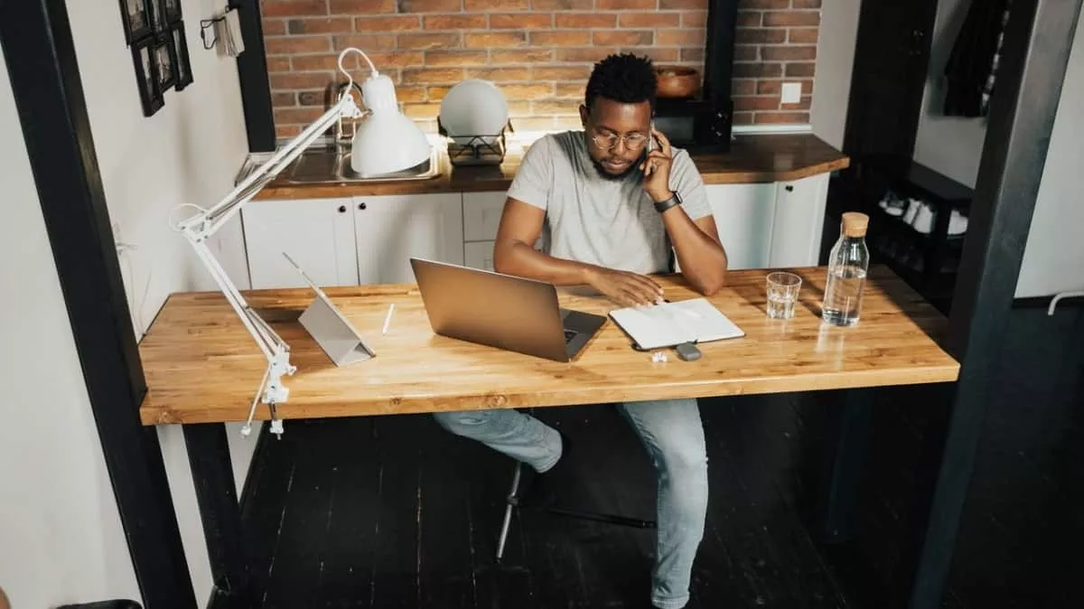 man sitting by a desk talking on phone complaining about slow internet