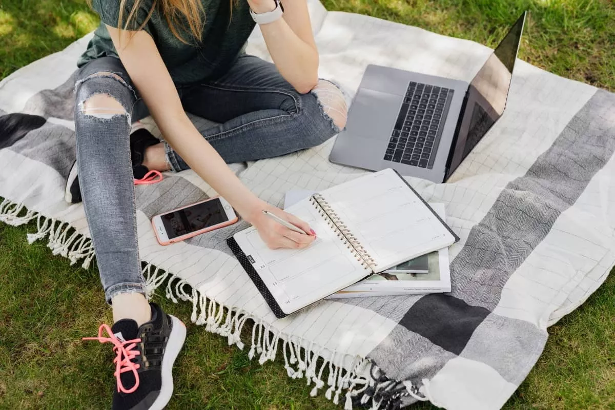 woman with laptop and notebook on sheets